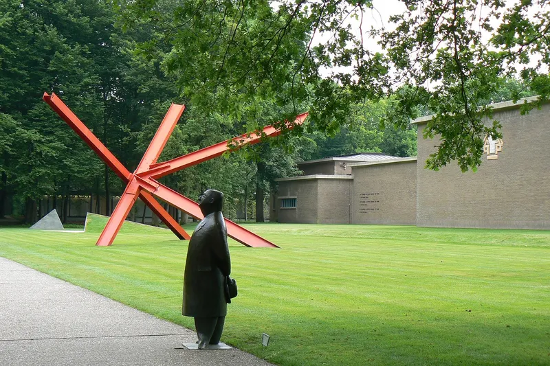 Escultura contemporánea de metal instalada sobre el césped del jardín del Museo Kröller-Müller.