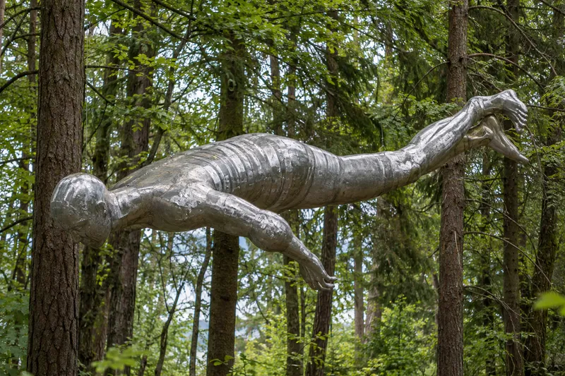 Escultura de aluminio suspendida de las ramas de varios árboles en el bosque de Ekebergparken.