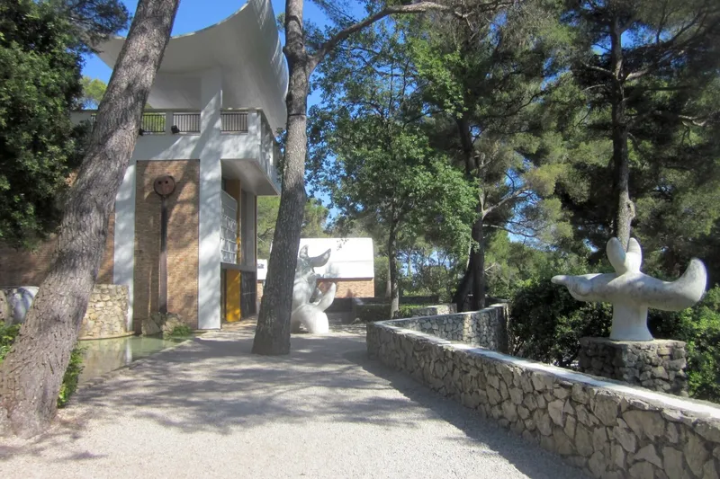 Jardín de museo de arte con esculturas al aire libre entre pinos