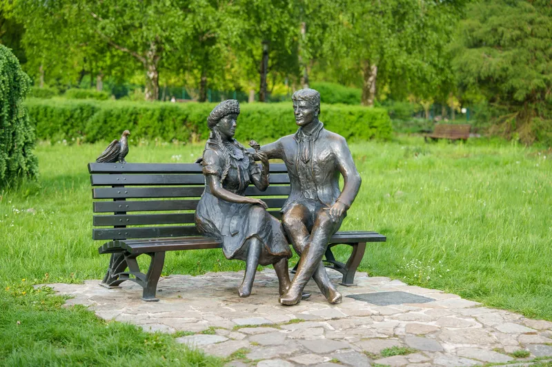 Escultura monumental de una pareja sentada en un banco, en un parque de arte al aire libre
