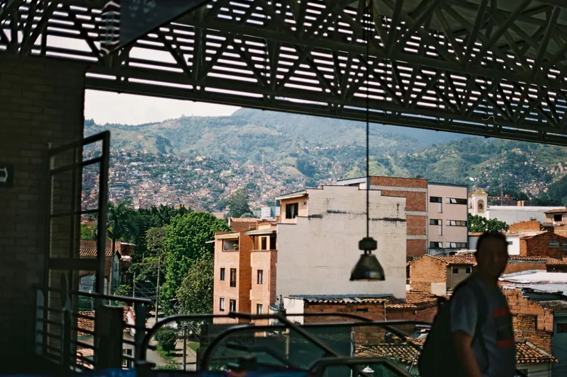 Escaleras mecánicas cubiertas en una ladera urbana con vistas a un barrio montañoso