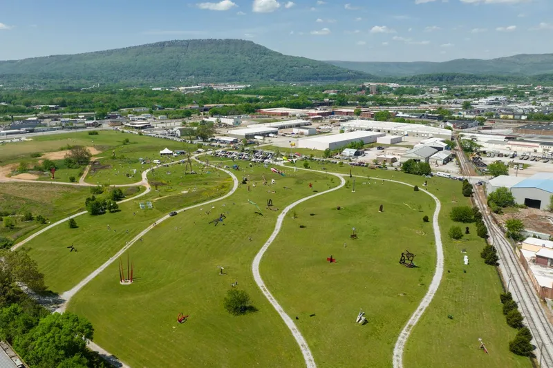 Parque de esculturas al aire libre con obras monumentales entre praderas y árboles